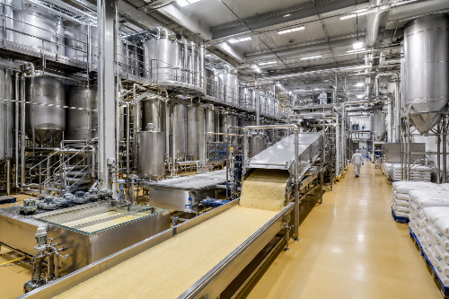 A gelatine factory with stainless steel vats and piping and a conveyer belt with gelatine powder on it