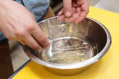 A person soaking gelatine leaves in water